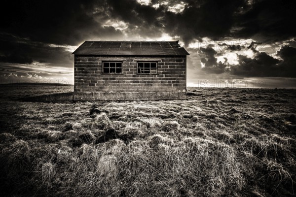 Sitting alone in a vast landscape, a rustic hut reveals the natural beauty of the Regional Nature Park of Volcans d'Auvergne under an ever-changing sky, Puy de Dome, Auvergne Rhone Alpes, France