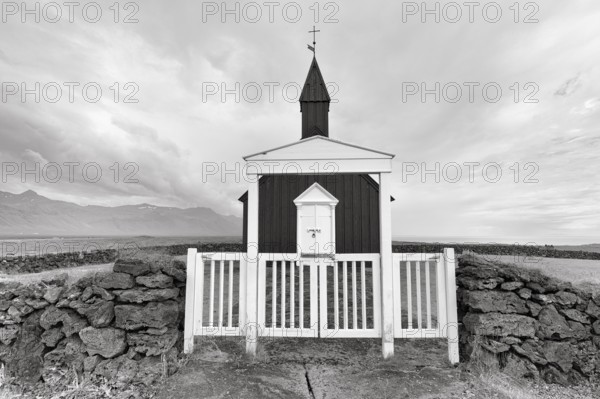 Traditional black church with white wooden door and stone wall, wooden church Budakirkja, monochrome, Búðir, Budir, Snaefellsnes Peninsula, Iceland
