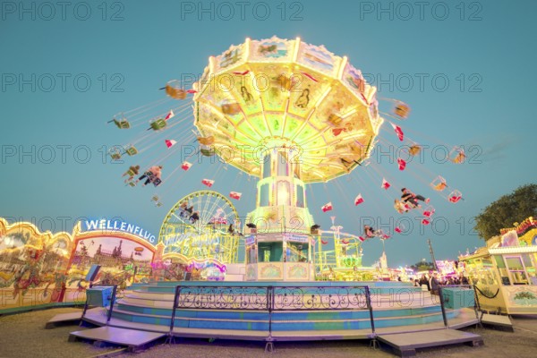A brightly lit chain carousel turns at a daytime fair, Chain carousel, Spring festival, Cannstatter Wellenflug, Illuminated, Cannstatter Wasen, Bad Cannstatt, Stuttgart, Baden-Württemberg, Germany
