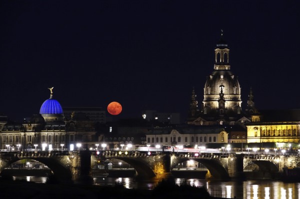 Glowing strawberry moon on 11 June 2025 over the Augustus Bridge in Dresden, between the Kunsthochschule and the Church of Our Lady, Saxony, Germany