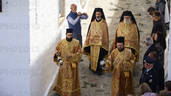 Clerics in richly decorated robes walk along a stone alley, spectators take photos, Orthodox ceremony, monks of St John's Monastery, ceremonial washing of feet, procession, Maundy Thursday, Megali Pempti, Chora, Patmos, Dodecanese, Greek Islands, Greece