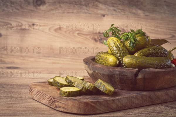 Pickled cucumbers in a wooden bowl with herbs and spices, close-up, rustic style
