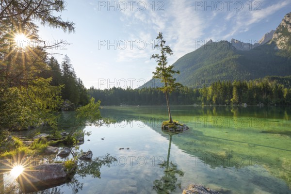 Sun star at sunrise at Hintersee near Ramsau in Berchtesgadener Land with sun star and reflection. The Hochkalter in the background