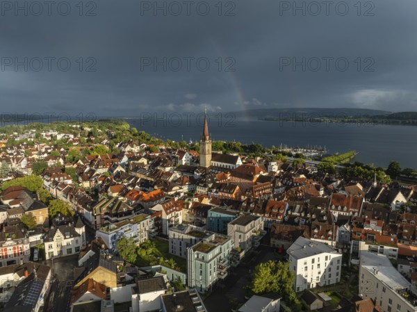 Luftbild von der Stadt Radolfzell am Bodensee mit der historischen Altstadt und dem Radolfzeller Münster nach einem Gewitterschauer von der Abendsonne angestrahlt, am Horizont ein Regenbogen, Landkreis Konstanz, Baden-Württemberg, Deutschland