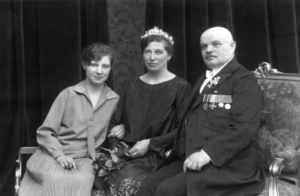 Family with a child, 1920, Two woman and a man in formal dress on a sofa, the man with medals, Historical photograph