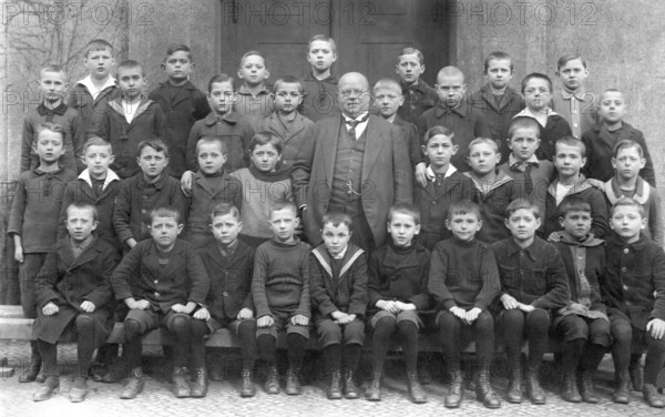 Group photo of a school class, ca. 1919, A group of schoolchildren posing with their teacher in front of a building, historical photo