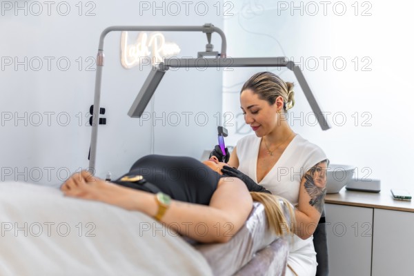 Beautician performing a permanent makeup treatment on a client's face, using a specialized device in a professional beauty salon
