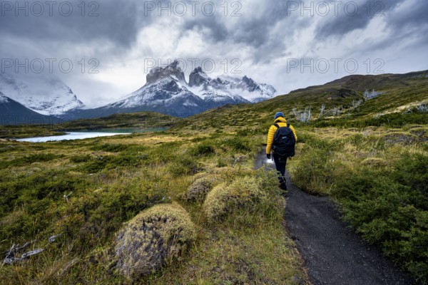 Hikers on the way to the Mirador de los Cuernos, Cuernos del Paine mountain range, dramatic sky, Torres del Paine National Park, Chile