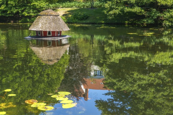 Floating duck breeding house with thatched roof, serose leaves, water reflection with villa from Contescarpe, Bremen ramparts, formerly part of the city fortifications with rampart and moat, today park, history, Bremen, Germany