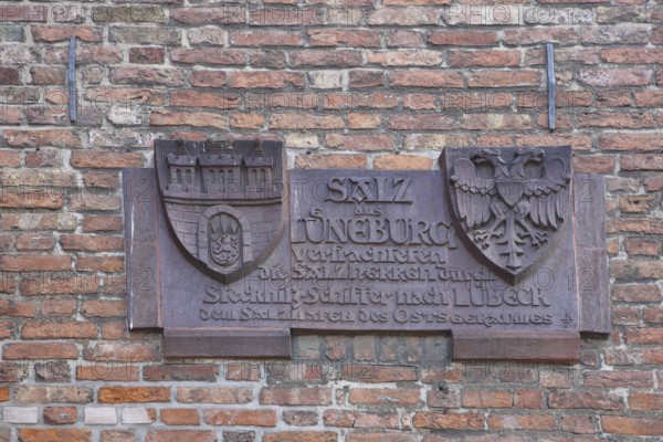 City coat of arms with inscription on the history of the city on the historical trade in salt, by ship via Stecknitz to Lüneburg, double eagle, production, sale, monochrome, brick wall, salt warehouse, old town, Lübeck, Schleswig-Holstein, Germany