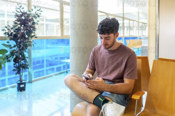 Patient sitting comfortably in a bright waiting room, using a smartphone to stay connected and informed while waiting for an appointment