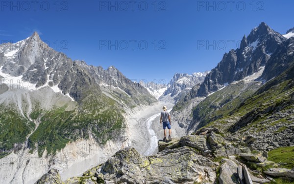 Picturesque mountain landscape with imposing mountain peaks and glaciers, mountaineer on hiking trail, Grand Balcon Nord, glacier tongue Mer de Glace, behind Grandes Jorasses, Mont Blanc massif, Montenvers, Chamonix, Haute-Savoie, France