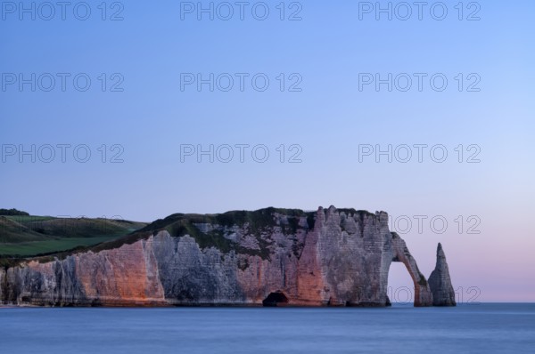 Rock arch Falaise or Porte d'Aval and rock needle Aiguille, illuminated, illuminated, Étretat, sea, steep coast, cliffs, chalk cliffs, alabaster coast, La Côte d'Albâtre, sunset, evening mood, atmospheric, Normandy, Seine-Maritime, France