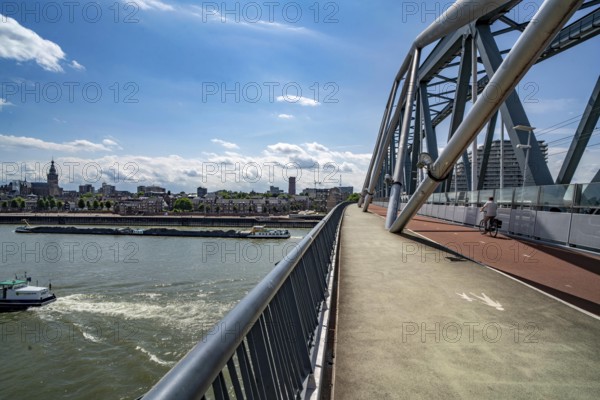 Cycle and pedestrian bridge Snelbinder Brug, over the river Waal near Nijmegen, was added to the existing railway bridge, fast cycle path connection from the city centre of Nijmegen and the new housing estates in the Waalsprong district, Netherlands