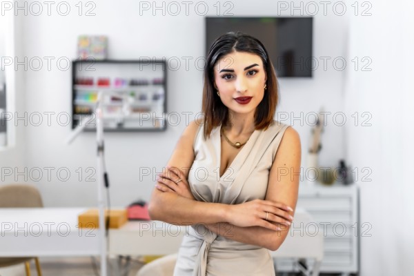 Young female entrepreneur posing with crossed arms in her hair and beauty salon, looking confident and professional