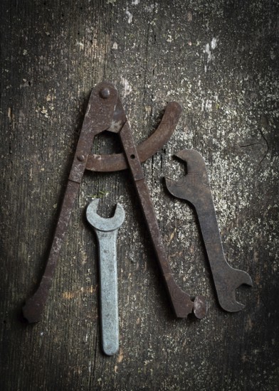 A collection of vintage tools, including a caliper and several wrenches, rests on a rustic wooden surface, highlighting their age and functional design attractive to enthusiasts and craftsmen alike