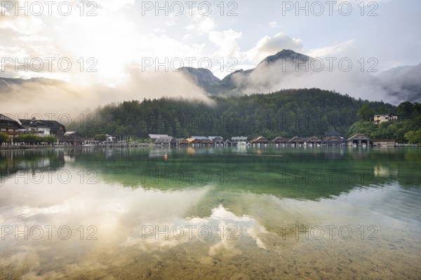 Mystical morning at Königssee in Schönau with boathouses. Sunrise and beautiful wafts of mist over the Königssee in the basin