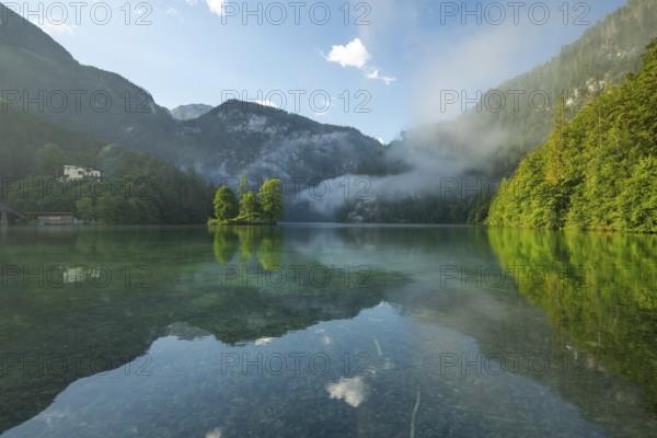 Mystical morning at Königssee in Schönau with boathouses and Christlieger. Sunrise and beautiful wafts of mist over the Königssee in the basin
