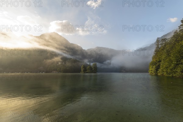 Mystical morning at Königssee in Schönau with boathouses and Christlieger. Sunrise and beautiful wafts of mist over the Königssee in the basin