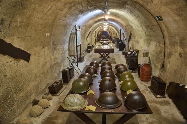 A tunnel with a row of helmets on a table, in the background exhibits, steel helmets, war museum, military museum, tunnel museum, Lakki, Leros, WW2, Dodecanese, Greek Islands, Greece