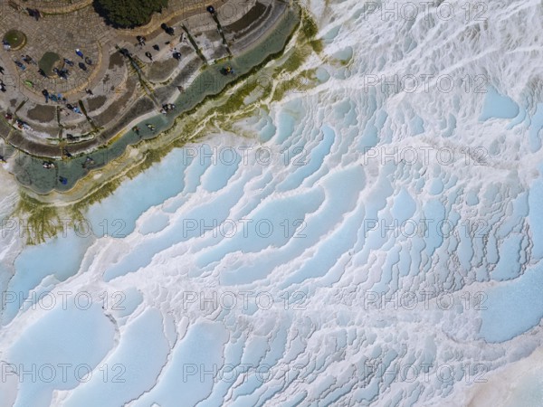 View of limestone terraces with blue water and small figures, surrounded by green vegetation, aerial view, sinter terraces, limestone terraces, travertine terraces, Pamukkale, Denizli, UNESCO World Heritage Site, Anatolia, Turkey