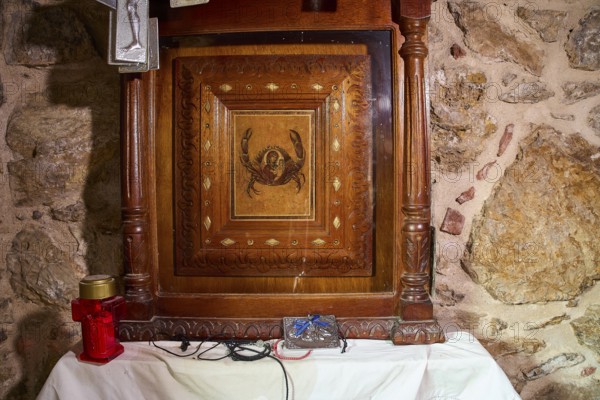 Legend, crab, shell fisherman, wood carving with crab motif in a chapel on an altar with candle, chapel, small church, Agia Kavouradena Monastery, Xirokambos, Leros, Dodecanese, Greek Islands, Greece