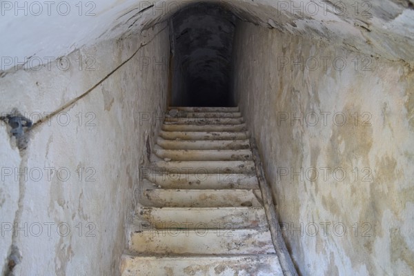 An old, narrow staircase leading deep into the darkness of an underground passage, Lost Place, Lago anti-aircraft battery, Bunker, Apitiki Mountain, Leros, Dodecanese, Greek Islands, Greece