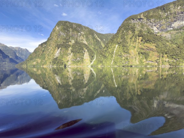 Mountains with reflections in the water against a blue sky in Doubtful Sound, South Island, New Zealand, Oceania