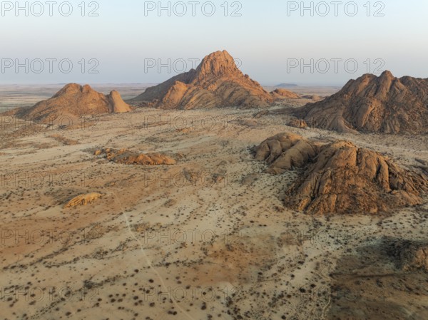 The isolated Spitzkoppe mountain (1728 m) majestically rises above the surrounding desert plains. At sunrise. Aerial view. Drone shot. Damaraland, Namibia