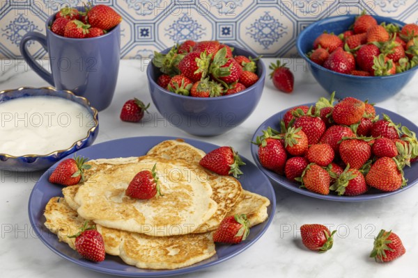 Pancakes with strawberries and yoghurt on blue crockery