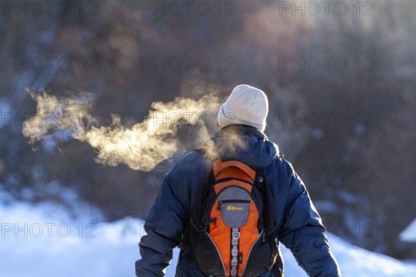 Person walking in very cold weather, Visual effect of the steam seen when exhaling in cold weather. City of Montreal, Province of Quebec, Canada, North America