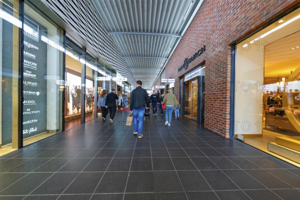 Visitors in the shopping centre surrounded by shops and modern architecture, Outlet City Metzingen, Germany
