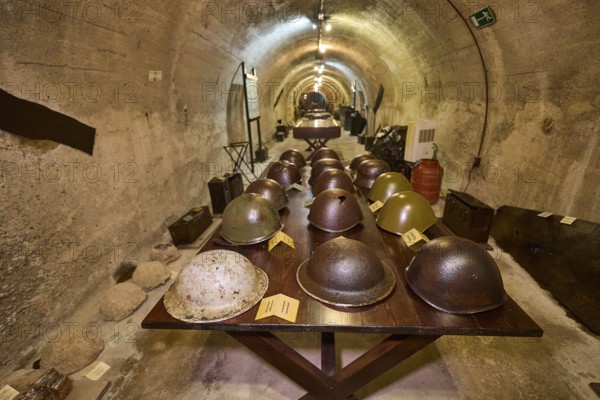 Table with various helmets in a long tunnel exhibition area, steel helmets, war museum, military museum, tunnel museum, Lakki, Leros, WW2, Dodecanese, Greek Islands, Greece