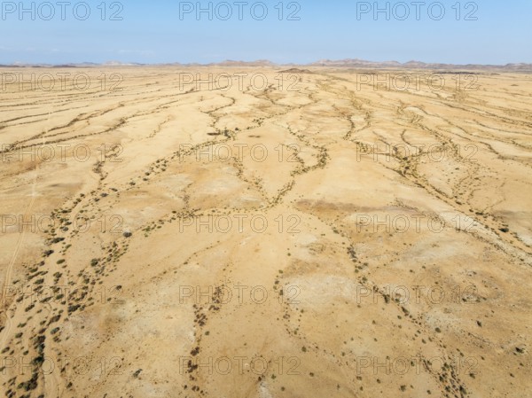 Arid desert plain and dried-up river beds with sparse vegetation. Aerial view. Drone shot. Gondwana Canyon Park. Namibia
