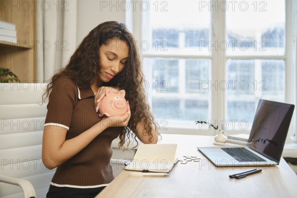 A young woman hugs a piggy bank with love and rejoices that her decision to save money led to financial well-being