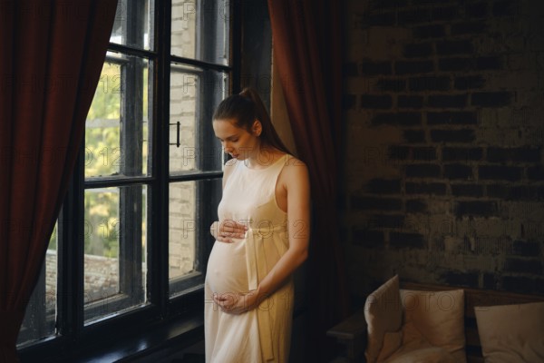A pregnant woman stands peacefully by a large window in a cozy room, gently cradling her baby bump. Warm evening light filters in, creating a serene atmosphere in her home