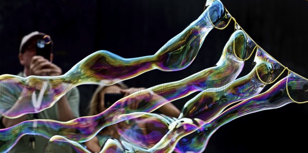 A man and a woman photograph iridescent soap bubbles in front of a black background, Recklinghausen, North Rhine-Westphalia, Germany