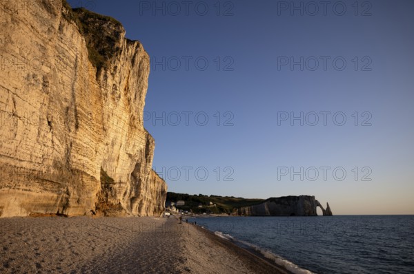 People on the beach, pebble beach, rock arch Falaise or Porte d'Aval, rock needle Aiguille, Étretat, sea, steep coast, cliffs, chalk cliffs, alabaster coast, La Côte d'Albâtre, evening mood, atmospheric, Normandy, Seine-Maritime, France