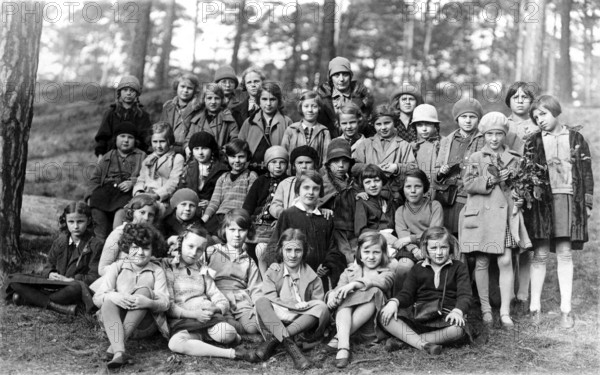 Group of children, 1920s, A large group of children sitting and standing in the forest, some in uniforms, Historical photo