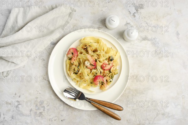 Fettuccine allo Scoglio, a delicious seafood pasta dish, is presented on a white plate with shrimp and herbs