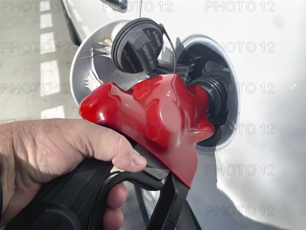Male hand holding gas pump nossle pumping gas into vehicle