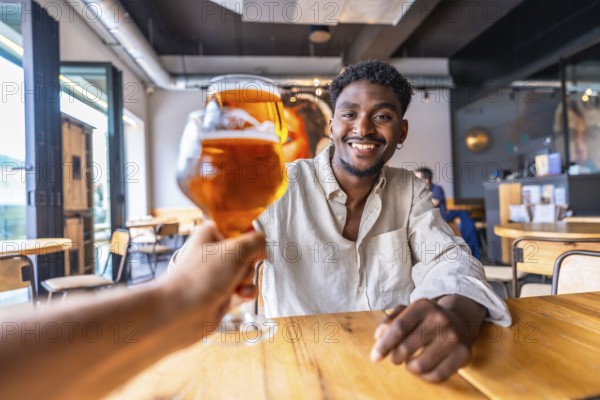 Waiter serving a refreshing glass of beer to a smiling young man in a stylish modern pub, creating a cheerful atmosphere for socializing