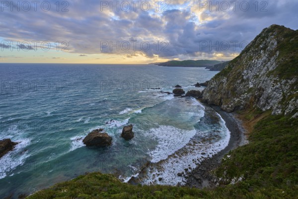 Cliffs and roaring waves in front of a colourful evening sky, summer, Nugget Point lighthouse, Ahuriri Flat, Otago, South Island, New Zealand