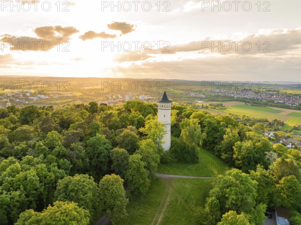 Tower with surrounding paths rises out of a green thicket under the sun, Engelberg Tower, Leonberg, Germany