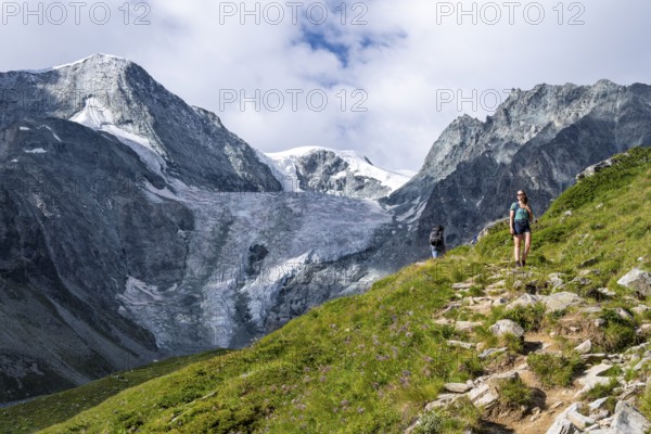 Mountaineer on a hiking trail, mountain landscape near Arolla, in the background mountain peak Mont Collon and glacier Glacier de Tsijore Nouve, Valais, Western Alps, Switzerland