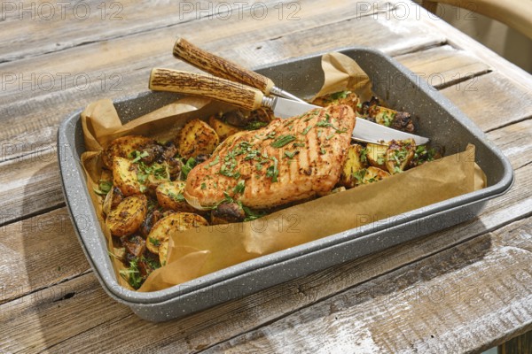 Roasted turkey breast is plated alongside an assortment of golden-brown vegetables, all garnished with fresh herbs. The rustic wooden table enhances the inviting atmosphere of the meal