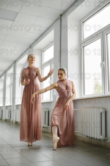 Two ballerinas in the corridor repeat movements, hone their skills