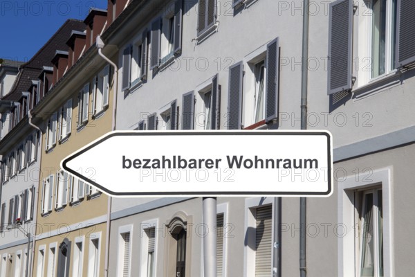(Photomontage) Sign with the inscription BEZAHLBARER WOHNRAUM in front of municipal apartment blocks