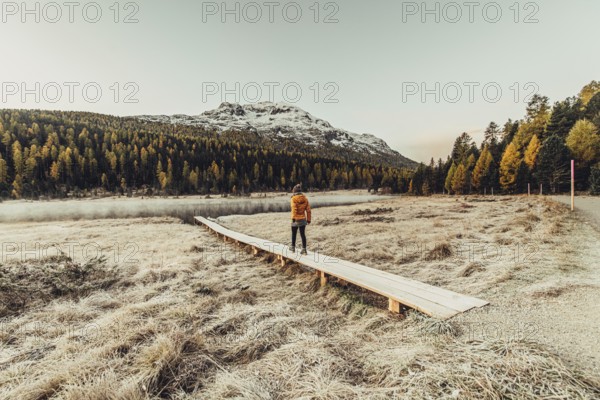 Young woman at Lake Staz near Sankt Moritz in the Engadine in Switzerland. Morning atmosphere with fog in autumn. Reflection of water