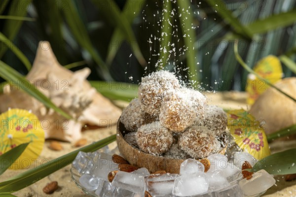 Coconut flakes fall on almond and chocolate confectionery in a coconut on ice cream with umbrellas on sand